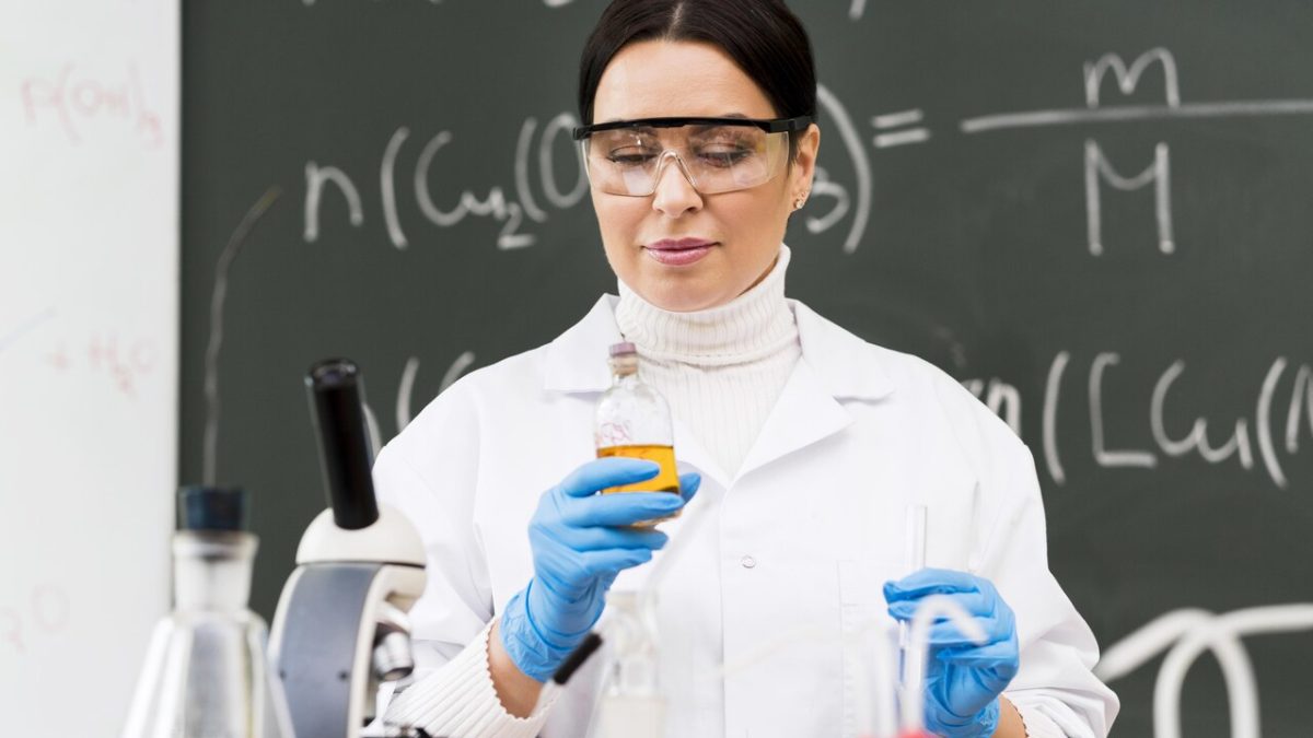 Estudante de química com elementos químicos, óculos de proteção e luvas