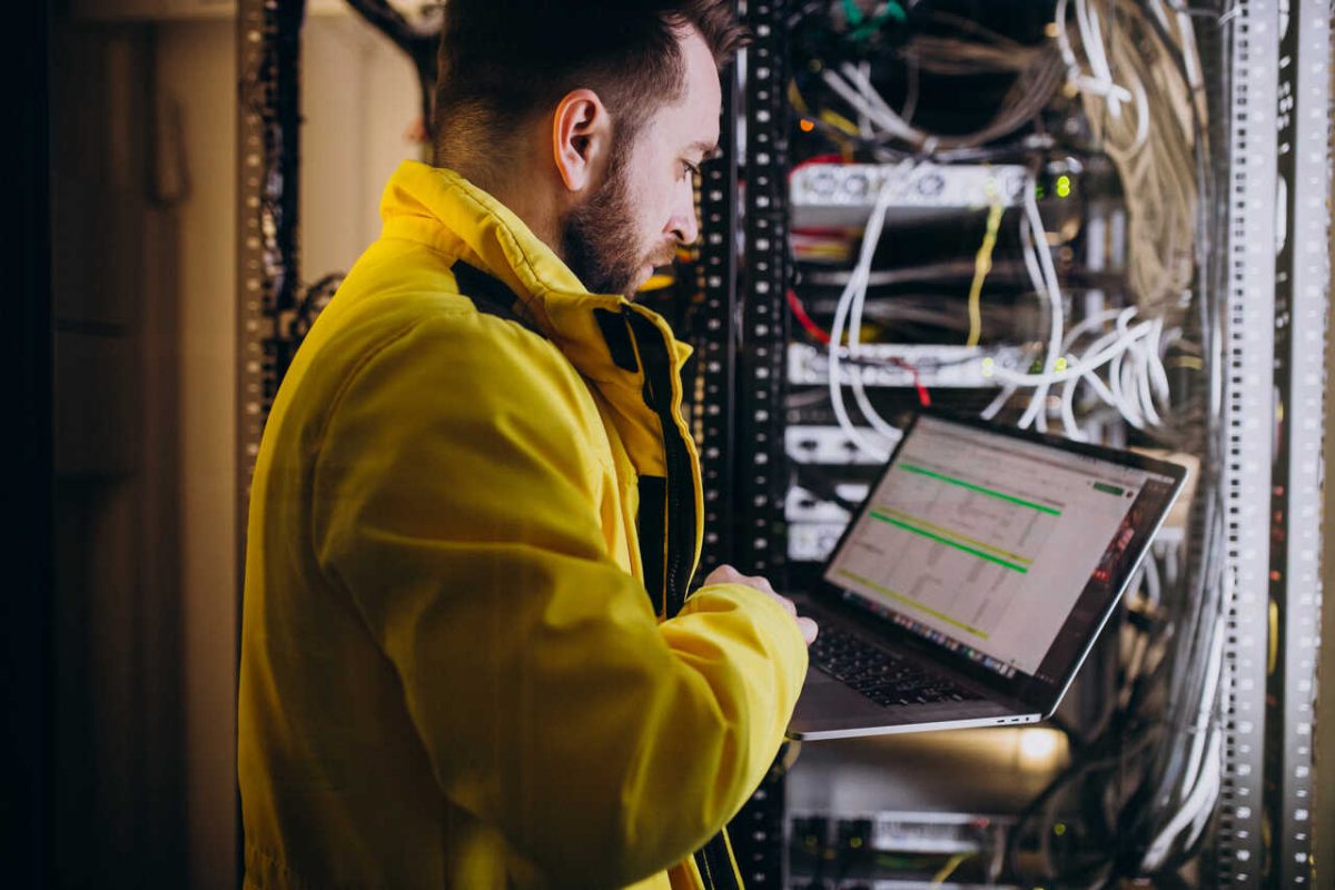 Técnico de redes de computadores ETEC 2024 faz teste de redes em notebook e afiações com casaco amarelo